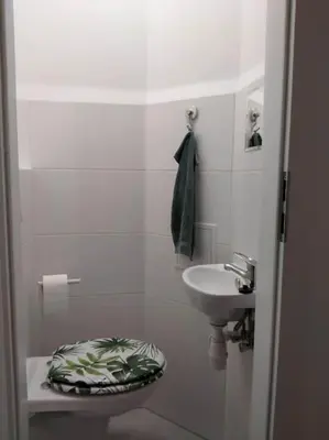 a white bathroom with a toilet and a sink at Parrot's Apartment in Kraków