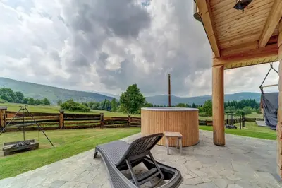 a patio with a chair and a table and a fence at Domek w Górach z Balią in Zawoja
