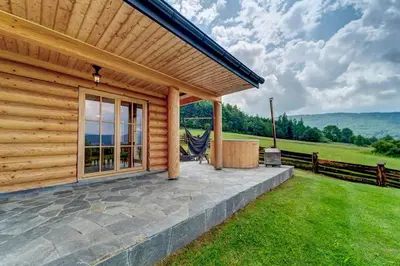 a wooden cabin with a patio and a fence at Domek w Górach z Balią in Zawoja
