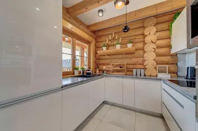 a kitchen with white cabinets and wooden walls at Domek w Górach z Balią in Zawoja