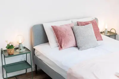 a bedroom with pink and white pillows on a bed at Kraków Trailside Apartments - by Upstairs in Kraków