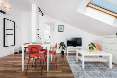 a white dining room with red chairs and a white table at Kraków Trailside Apartments - by Upstairs in Kraków