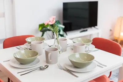 a table with plates and cups and a vase with flowers at Kraków Trailside Apartments - by Upstairs in Kraków