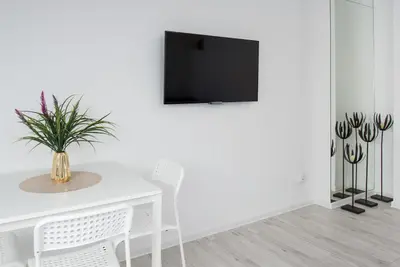a white dining room with a white table and a tv at Długa 14 by Homeprime in Kraków