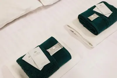 two towels sitting on a bed with a cell phone at City of the Kings-Edith in Kraków