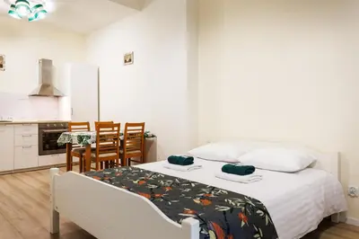 a bedroom with a white bed and a kitchen at City of the Kings-Edith in Kraków
