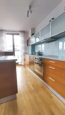 a large kitchen with wooden cabinets and a wooden floor at Starowiślna 52 by Homeprime in Kraków