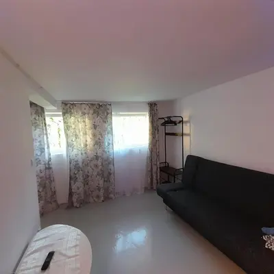 a living room with a black couch and two windows at Domek Muchomorek 1km od Energylandii in Zator