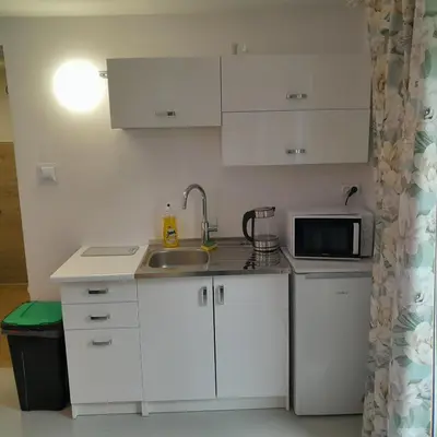 a kitchen with white cabinets and a sink and a microwave at Domek Muchomorek 1km od Energylandii in Zator