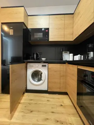 a kitchen with a washing machine and a microwave at Revesen Premium Apartments in Kraków