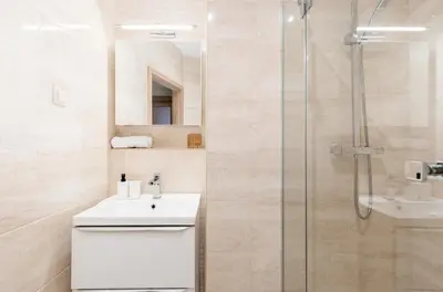 a bathroom with a sink and a shower at Revesen Premium Apartments in Kraków