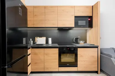 a kitchen with a black counter top and wooden cabinets at Revesen Premium Apartments in Kraków