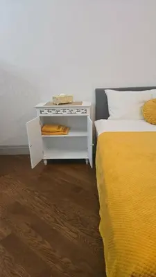 a bed with a white nightstand next to a yellow bed at ViP APART CRACOW in Kraków