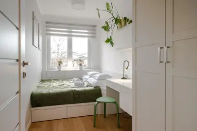 a small bedroom with a bed and a green stool at Quiet Courtyard Apartment near Old Town in Kraków