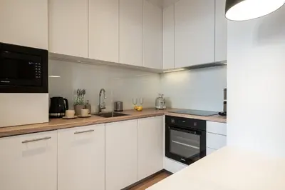 a kitchen with white cabinets and a black appliance at Quiet Courtyard Apartment near Old Town in Kraków