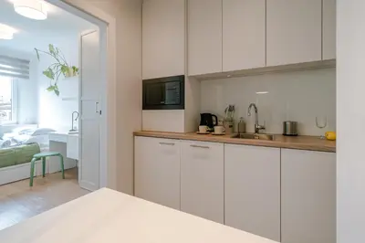 a kitchen with white cabinets and a living room at Quiet Courtyard Apartment near Old Town in Kraków