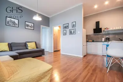 a living room with a couch and a kitchen at Stylowy apartament w samym centrum Krakowa in Kraków