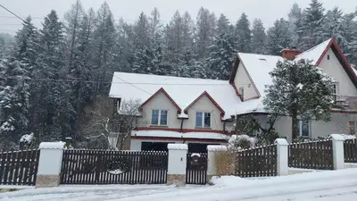 a house with a fence covered in snow at Beskidzka Apartments in Sucha Beskidzka
