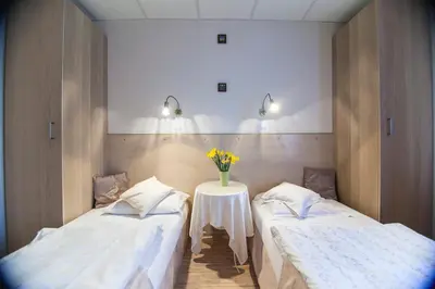 a room with two beds and a table with flowers at Akacja Pokoje Gościnne in Kraków