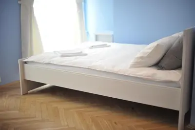 a white bed in a room with a wooden floor at Vinci in Kraków