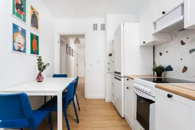 a kitchen with white cabinets and a table and blue chairs at Pretty 4 Bedroom Apartment in City Center - by Upstairs in Kraków