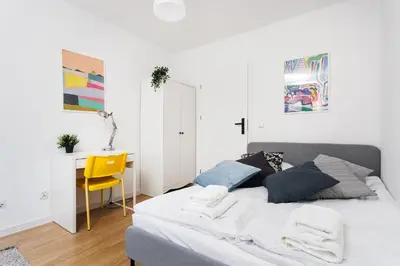 a bedroom with a bed with a yellow chair and a desk at Pretty 4 Bedroom Apartment in City Center - by Upstairs in Kraków