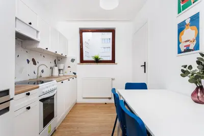 a kitchen with white cabinets and a table with blue chairs at Pretty 4 Bedroom Apartment in City Center - by Upstairs in Kraków