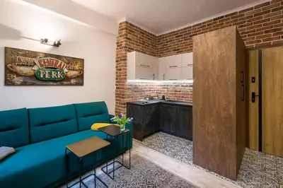 a living room with a blue couch and a kitchen at Feel like home in Kraków in Kraków