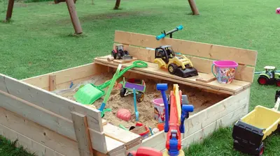 a wooden sandbox with toys in it in a yard at Noclegi i Agroturystyka Dorota Rusnak in Poręba Wielka