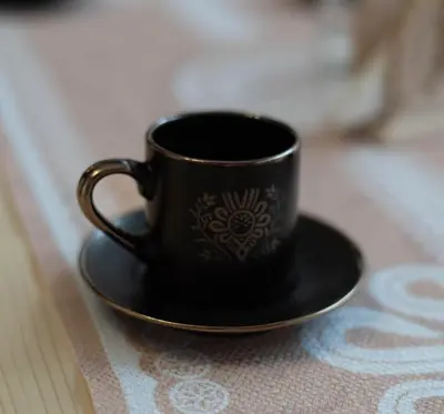 a black coffee cup on a plate on a table at Noclegi i Agroturystyka Dorota Rusnak in Poręba Wielka