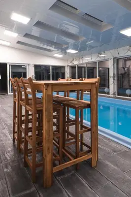 a wooden table and chairs next to a swimming pool at ŁOSOSINA 365 Dom z basenem in Łososina Dolna