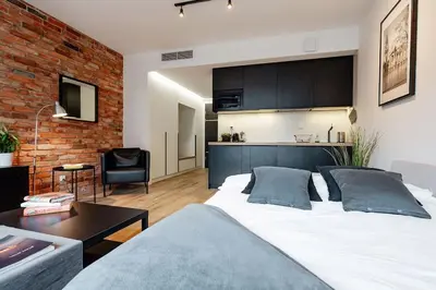 a bedroom with a large white bed and a brick wall at Luxury standard apartment in Cracow in Kraków