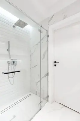 a white bathroom with a shower with a glass door at Luxury standard apartment in Cracow in Kraków