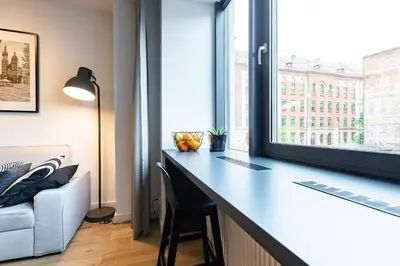 a desk with a chair in a room with a window at Luxury standard apartment in Cracow in Kraków