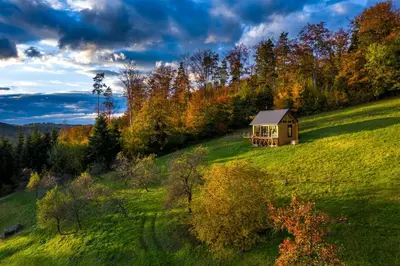 a small house on a hill in a field at Czas i Las Glamping in Sadek