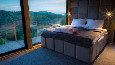 a bed in a room with a large window at Czas i Las Glamping in Sadek