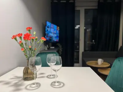 two wine glasses and a vase with flowers on a table at Parkcity Kraków in Kraków