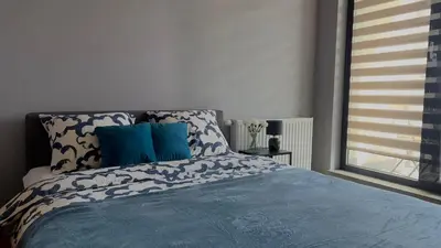 a bedroom with a bed with blue sheets and a window at Parkcity Kraków in Kraków