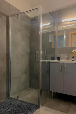 a bathroom with a glass shower and a sink at Parkcity Kraków in Kraków