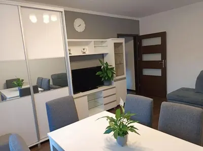 a living room with a table and chairs and a television at Apartament u Oli i Laury in Kraków