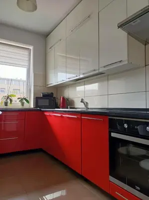 a kitchen with red cabinets and a black oven at Apartament u Oli i Laury in Kraków