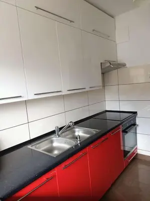 a kitchen with a sink and red cabinets at Apartament u Oli i Laury in Kraków