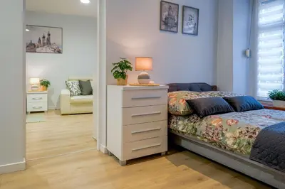 a bedroom with a bed and a dresser with a lamp at Old Town WAWEL II Premium Apartments in Kraków