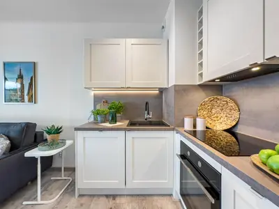 a kitchen with white cabinets and a counter top at Nowoczesny Apartament w okolicy Tauron Areny in Kraków