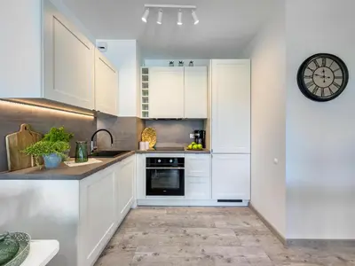 a kitchen with white cabinets and a clock on the wall at Nowoczesny Apartament w okolicy Tauron Areny in Kraków