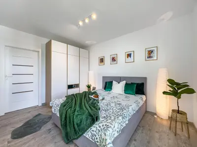 a bedroom with a bed with a green blanket on it at Nowoczesny Apartament w okolicy Tauron Areny in Kraków