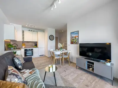 a living room with a couch and a tv and a table at Nowoczesny Apartament w okolicy Tauron Areny in Kraków