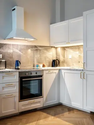 a kitchen with white cabinets and a stove at Tyzenhauz Suites Topolowa in Kraków