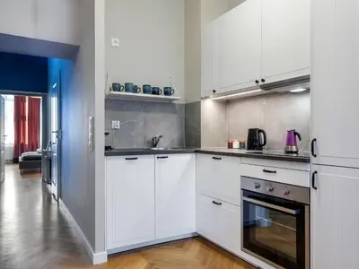 a white kitchen with white cabinets and appliances at Tyzenhauz Suites Topolowa in Kraków