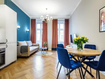 a living room with a table and blue chairs at Tyzenhauz Suites Topolowa in Kraków